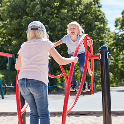 Die Kinder benutzen eine Wippe, auf der sie stehen und sich an beiden Enden festhalten müssen. 